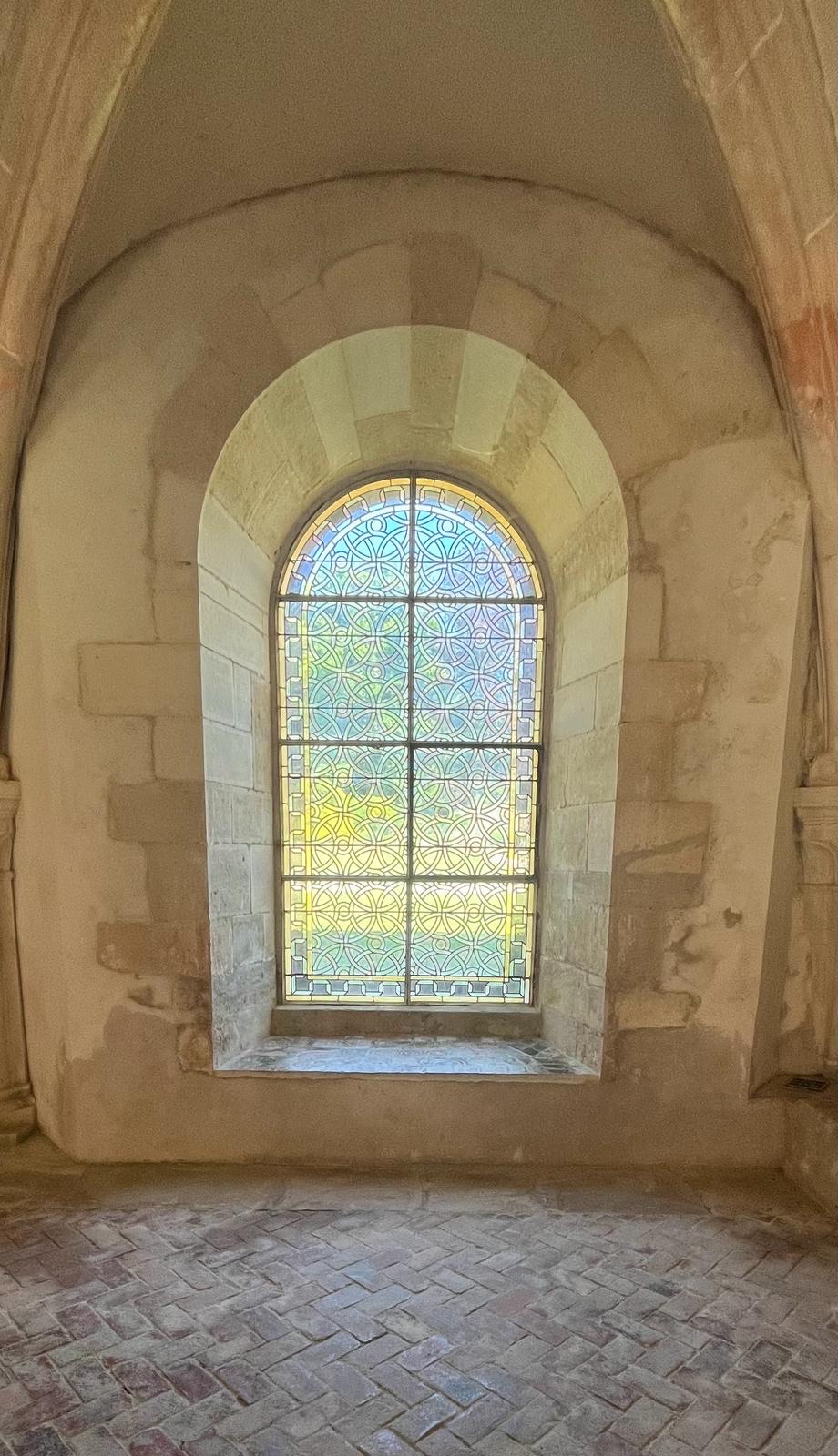 Arched stained-glass window in a stone abbey wall at the venue.